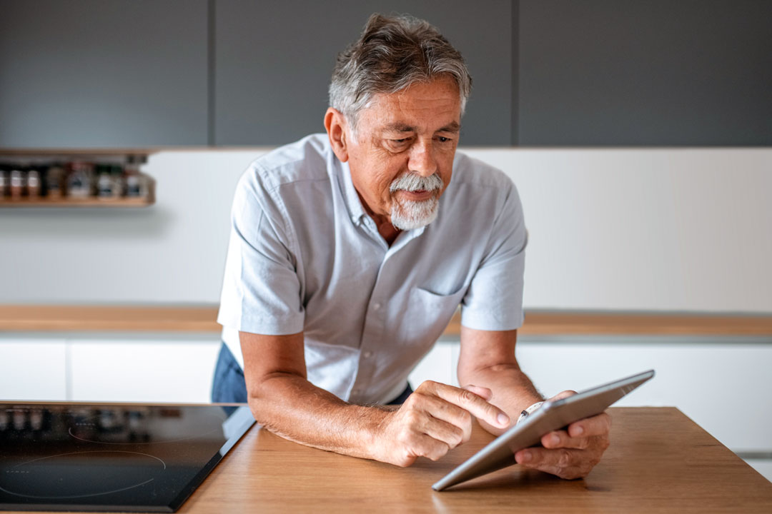 senior-man-kitchen-tablet Man on tablet playing minecraft, for sure