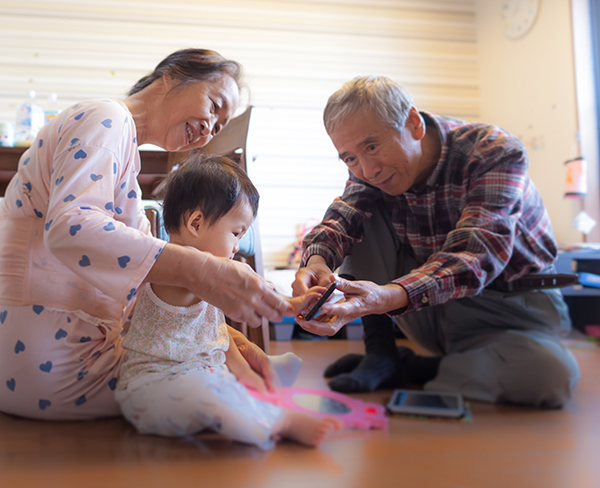 Asian grandmother grandfather and granddaughter are playing a smartphone together at home, Tokyo, Japan..Granddaughter shows interested in tech devices.smart