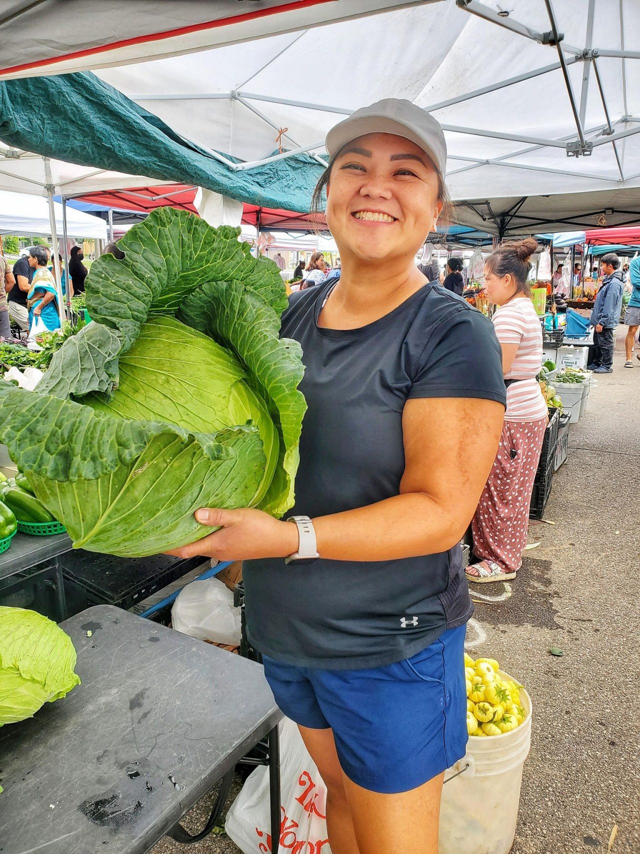 Image of Mang Vang, an asian, female-presenting person holding a very large cabbage.